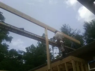 Carpenter setting a ridge beam over a new addition frame — Ice Dam Removal by Roofing Brothers in Dumfries