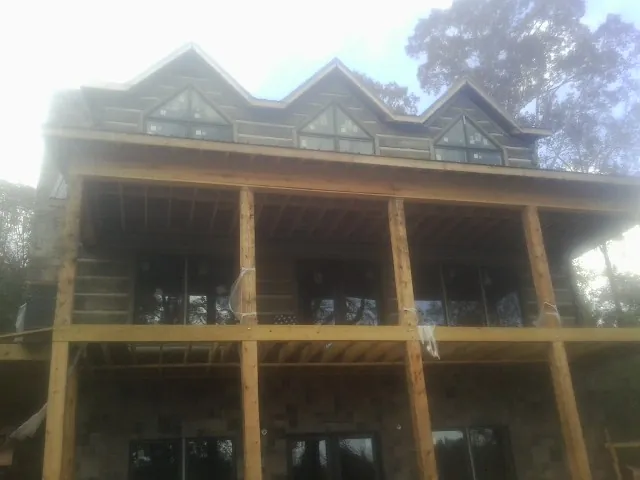 Dormers and porch framing on a large log home under construction — Roof Coating work by our crew in Dumfries