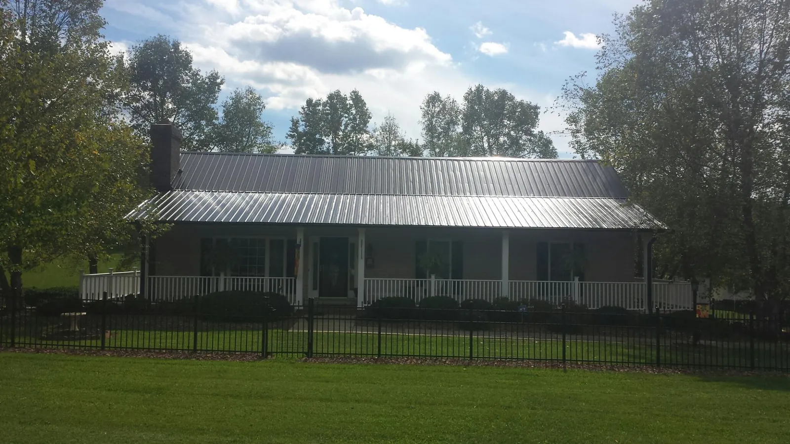 Gray metal roof on a brick ranch with a full width front porch — Gutter Guard Installation work by our crew in Dumfries