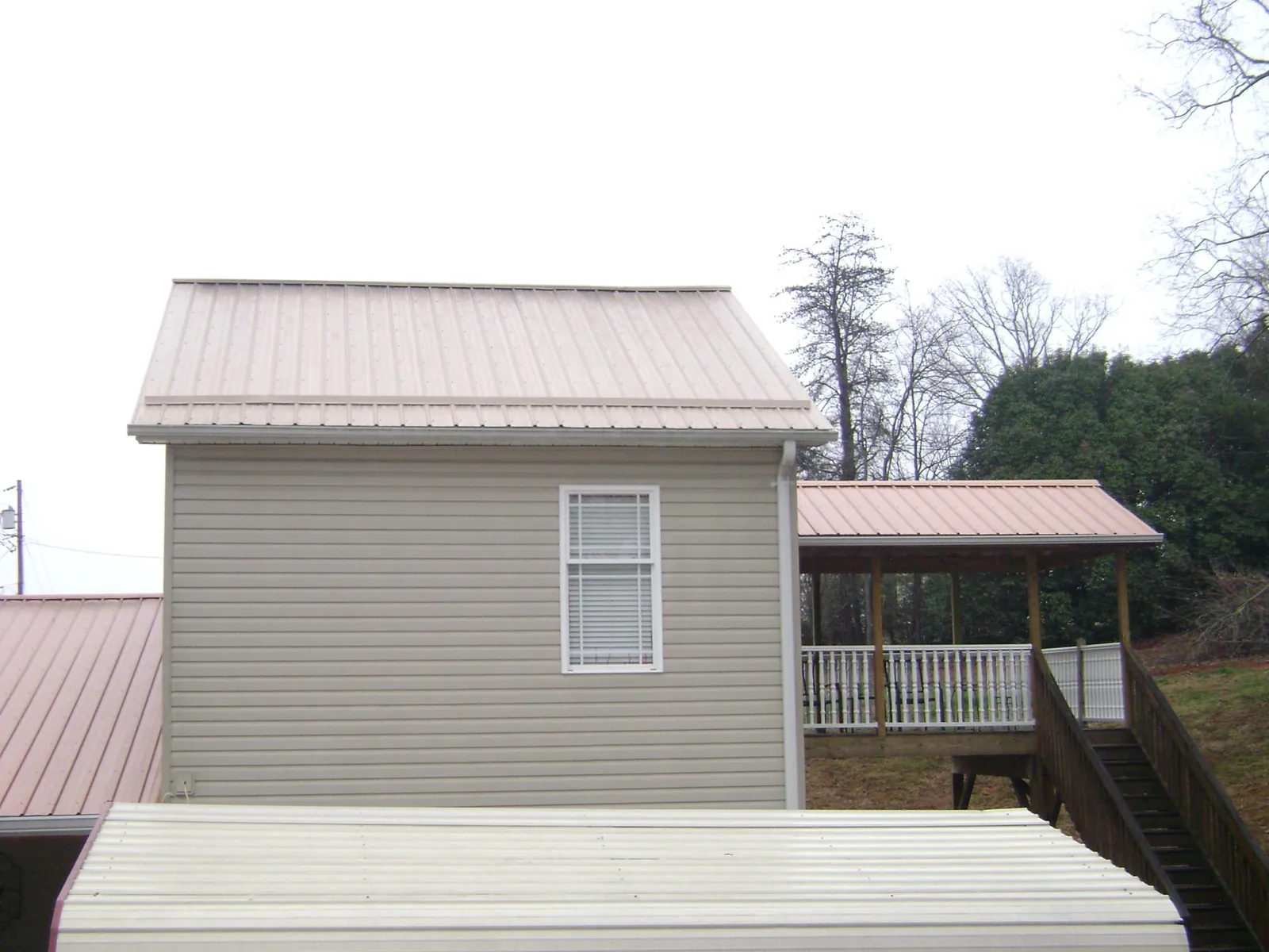 Tan metal roofs on a two story addition and attached porch, from a Roof Replacement job in Dumfries